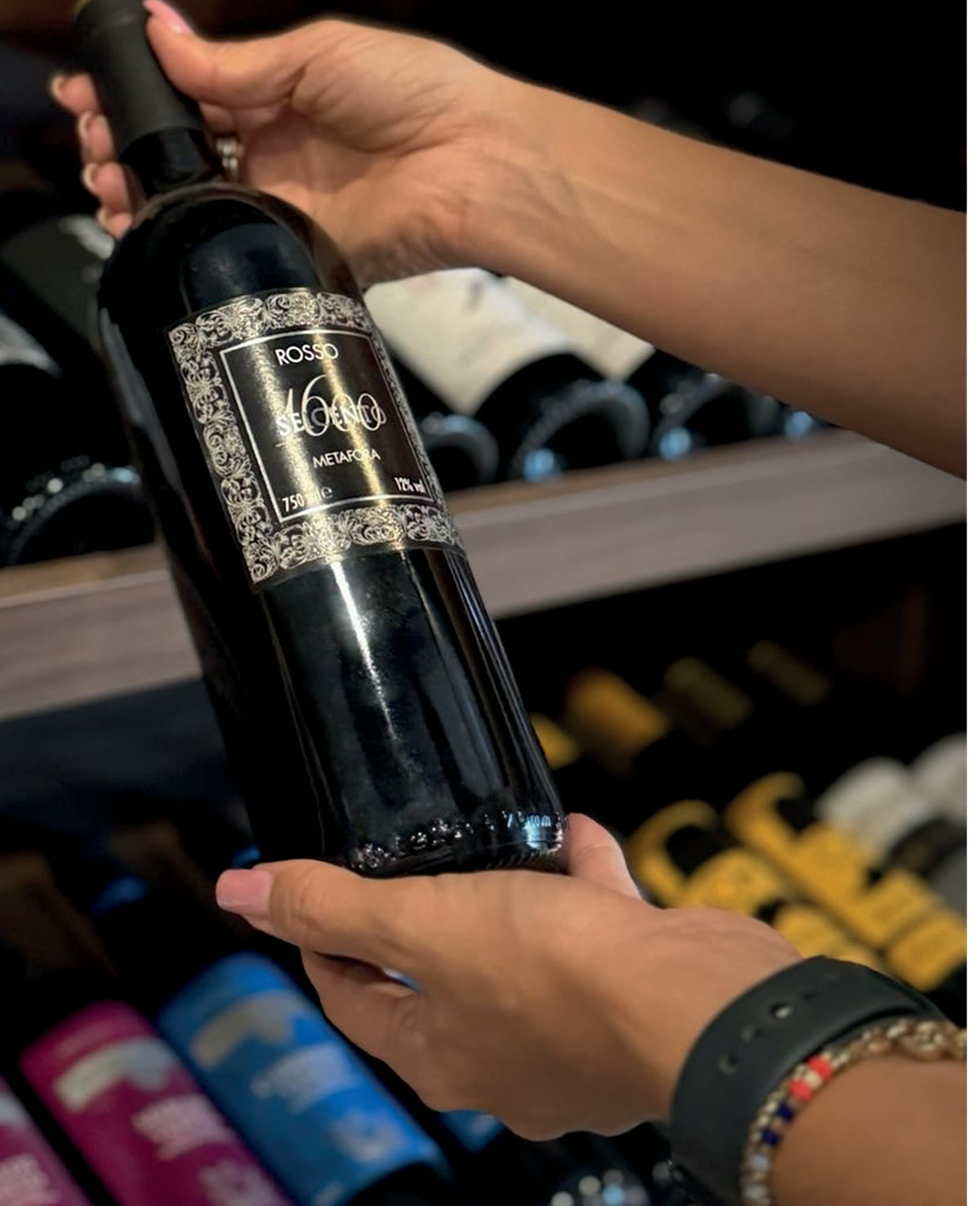 Garrafa de vinho tinto sendo retirada da adega da Itaim